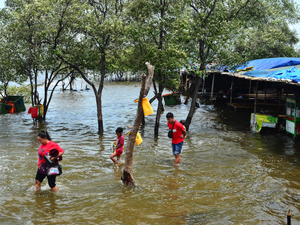 People is seen walking at a beach while sea level rising in Jakarta, Indonesia, December 19, 2024.