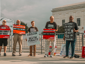 a group of people holding signs in front of a fence