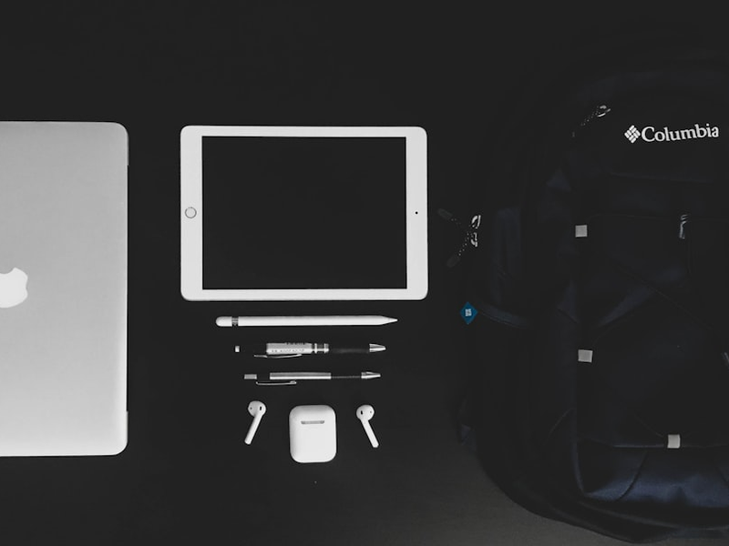 MacBook Air and white iPad near black Columbia backpack