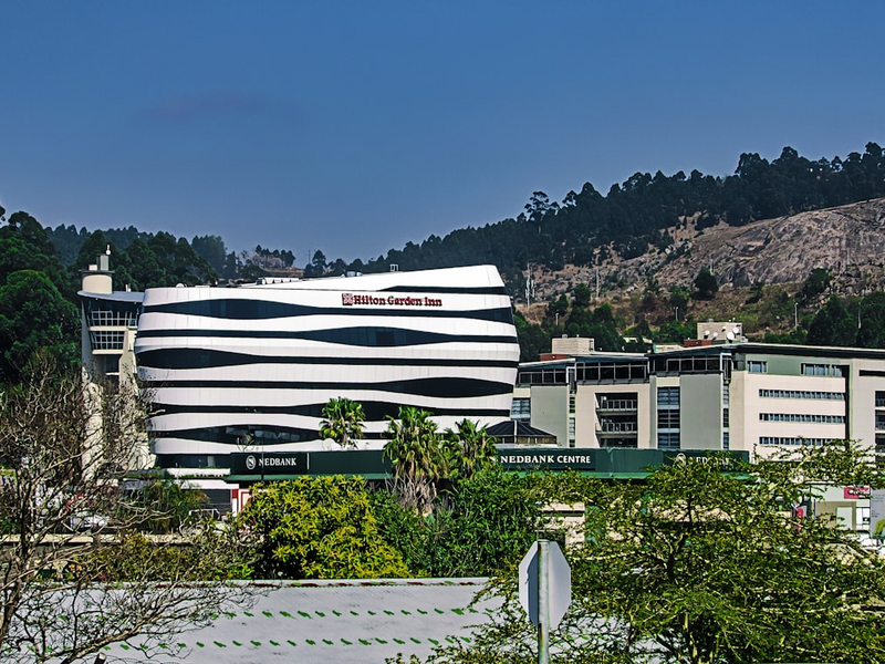 A modern building stands against a backdrop of mountains.