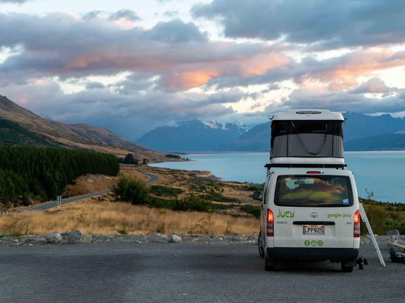 a van parked on the side of a road next to a body of water