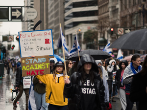 At the Unity Rally, a march against antisemitism held in San Francisco, an activist holds up a sign stating "STAND AGAINST HATE", while another holds up a sign state stating "FOR A CEASEFIRE ASK FOR YAHYA SINWAR" as a statement against Hamas efforts to block a durable, honest ceasefire. Other demonstrators hold up Israeli flags.