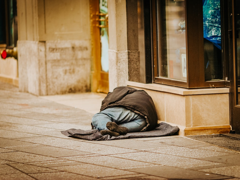 man in gray hoodie lying on gray concrete floor during daytime