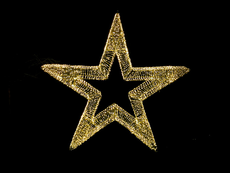 A luminous golden star with a glowing wireframe design isolated on a black background, creating a stark contrast and a sense of celebration or festivity.
