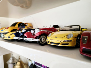 Toy cars are lined up on a white shelf.