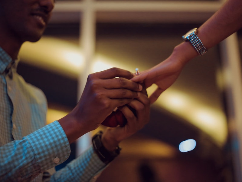 man putting ring on woman's hand