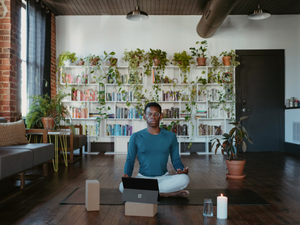 a man sitting on a yoga mat with a laptop in front of him