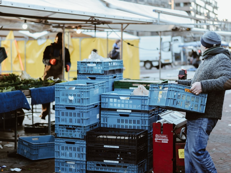 man carrying blue crates