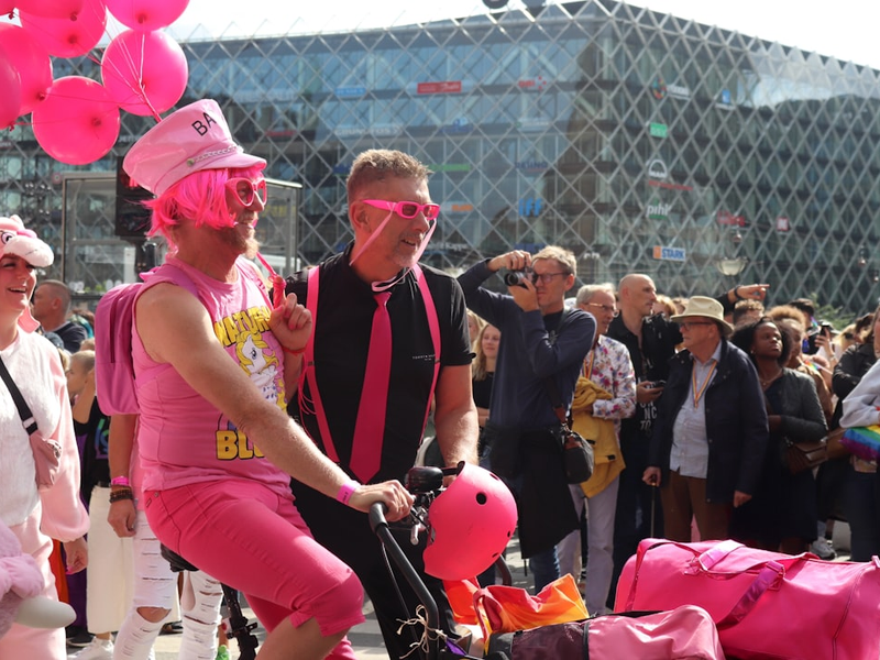 a man riding a bike with pink balloons on the back of it