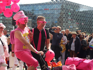 a man riding a bike with pink balloons on the back of it