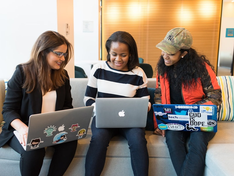 three women sitting on sofa with MacBook