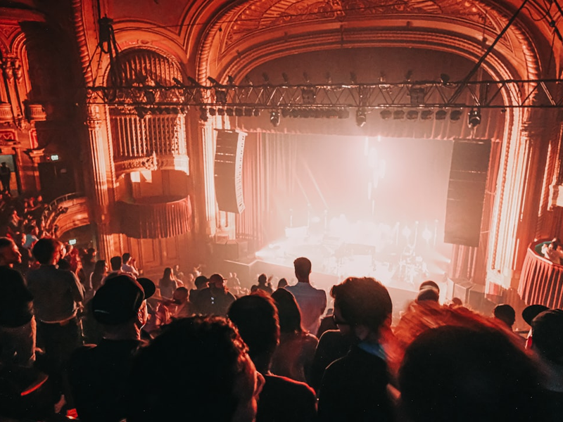 a group of people in a room with a stage and a large screen