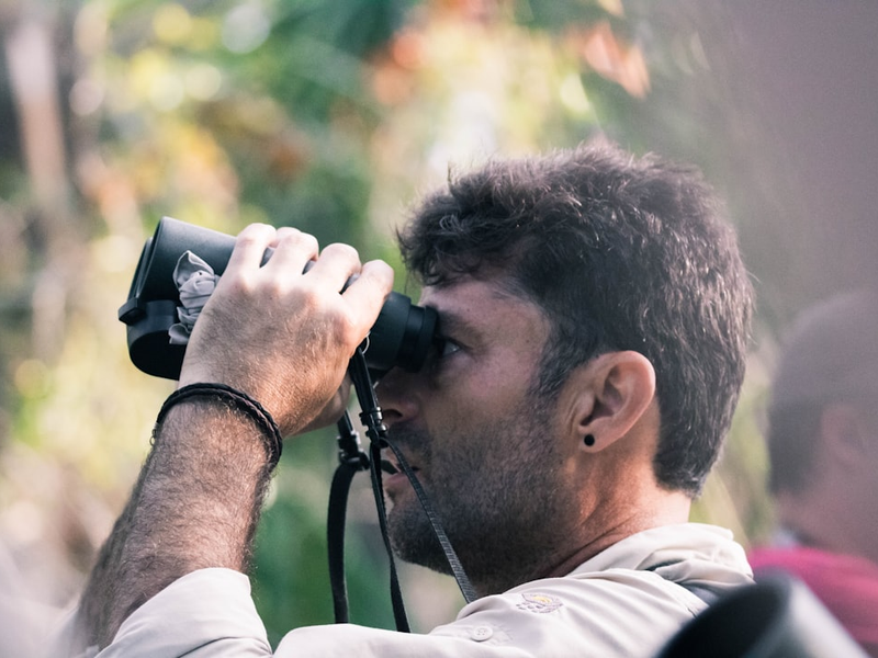 man using black binoculars at daytime