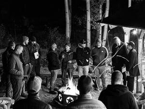 Men gather around a fire at night