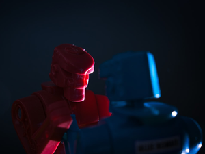 Close up of the Red Rocket robot from the toy Rock'em Sock'em Robots and the backside of the Blue Bomber, with side lighting.