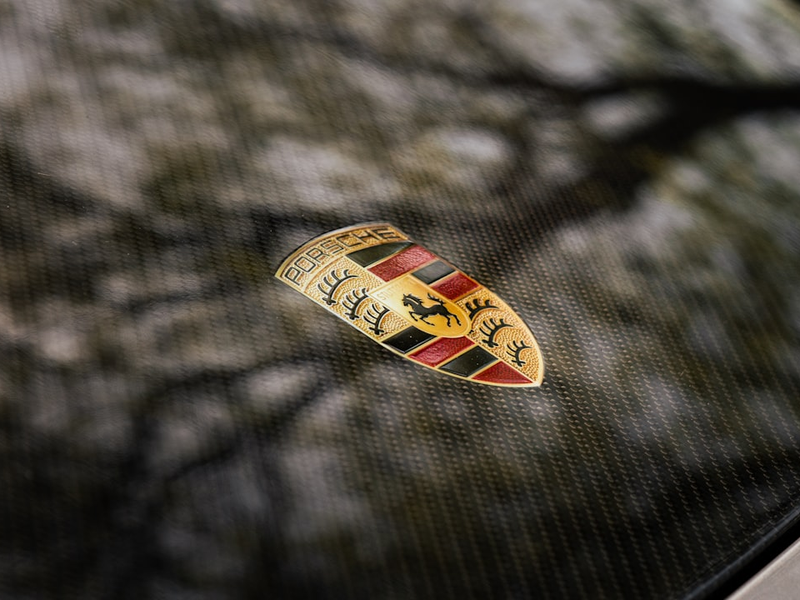 A porsche emblem rests on a textured surface.