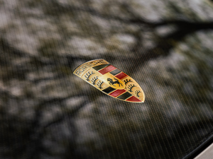 A porsche emblem rests on a textured surface.
