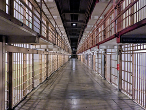 A long hallway in a jail with bars on the sides