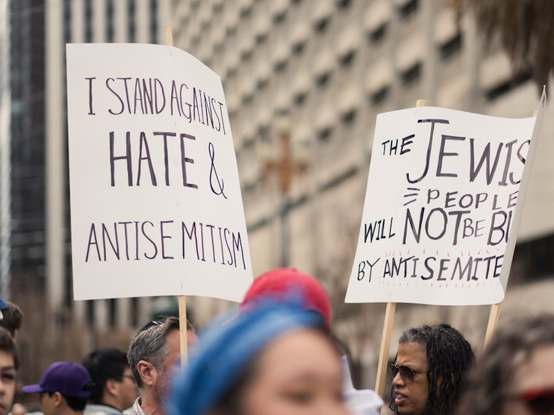 People hold up signs stating "I STAND AGAINST HATE & ANTISEMITISM" AND "THE JEWISH PEOPLE WILL NOT BE BULLIED BY ANTISEMITES" at the Unity Rally, a march against antisemitism in San Francisco.