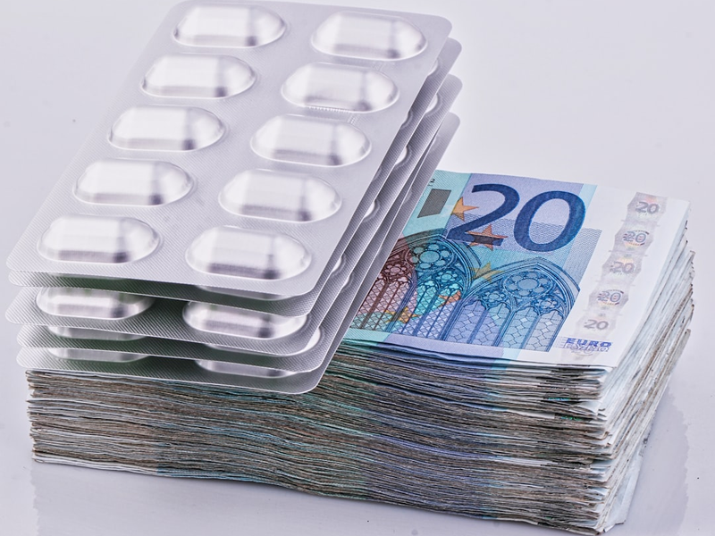 a stack of 20 euro bills next to a pack of 20 pills