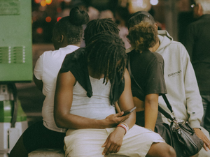 Three people sitting together looking at a phone.