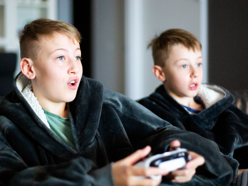 two young boys sitting on a couch playing a video game