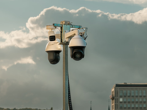 Surveillance Cameras Urban Security Pole City Background. Set of modern CCTV cameras mounted on a metal pole against a cloudy sky in an urban environment. Public safety technology used for monitoring streets and traffic in city areas