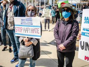man in black jacket holding white and blue signage