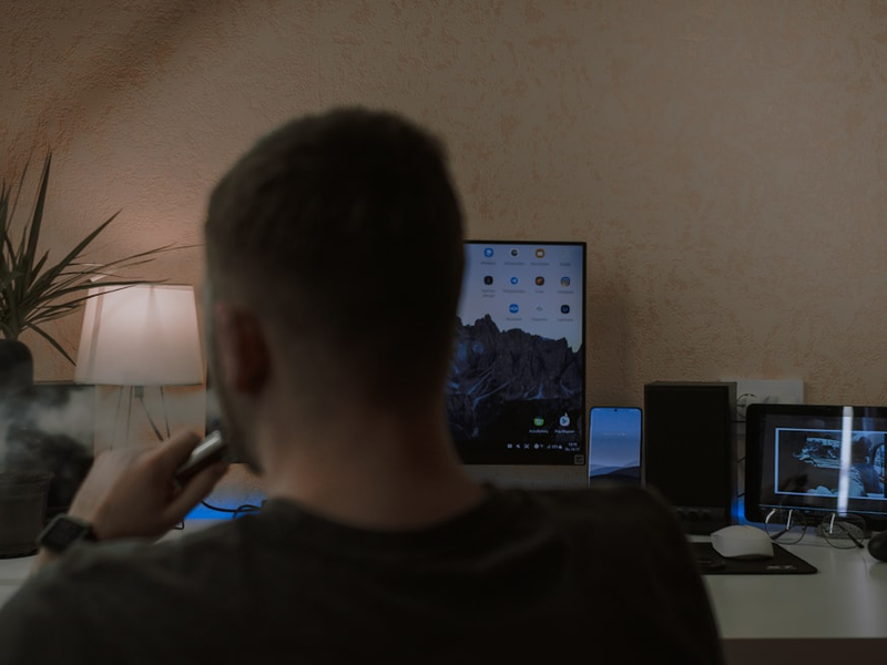 a man smoking a cigarette in front of a computer