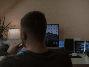 a man smoking a cigarette in front of a computer