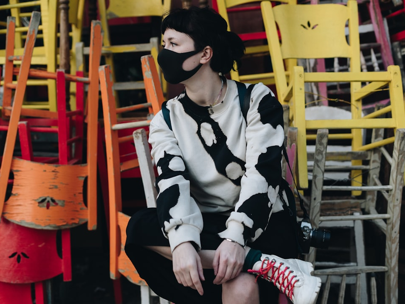 a woman sitting on a chair wearing a face mask