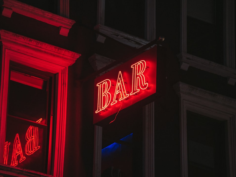 a red bar sign lit up in the dark