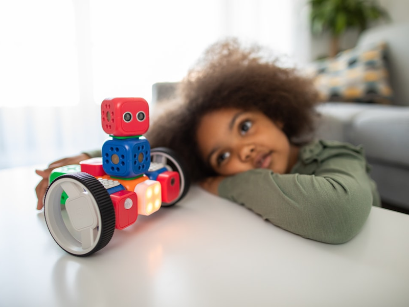 boy lying on bed playing with red and blue toy truck