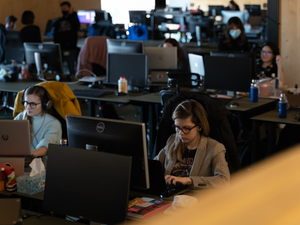 Female colleagues working on computers in crowded office.