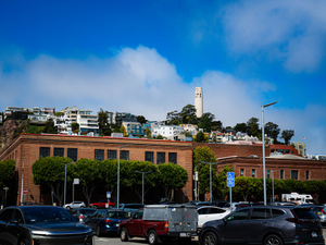 City buildings on a hill under a blue sky.