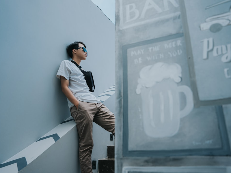 a man leaning against a wall next to a sign