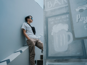 a man leaning against a wall next to a sign