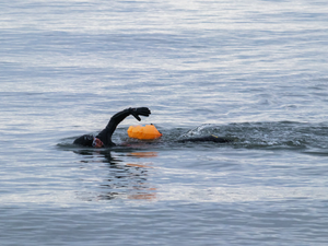open water swimmer in the sea with orange float device