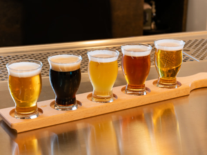 a row of beer glasses sitting on top of a wooden tray