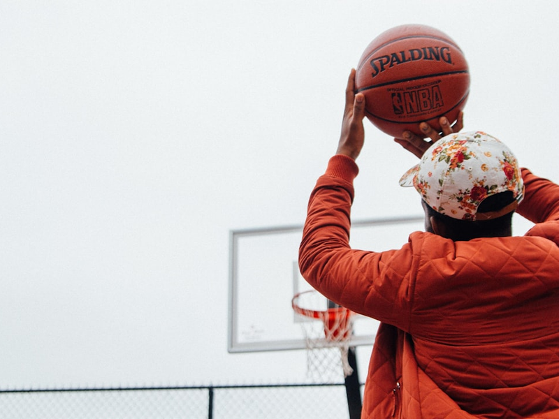 person holding basketball looking at basketball hoop system