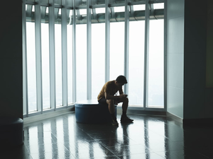 man sitting on ottoman chair near window