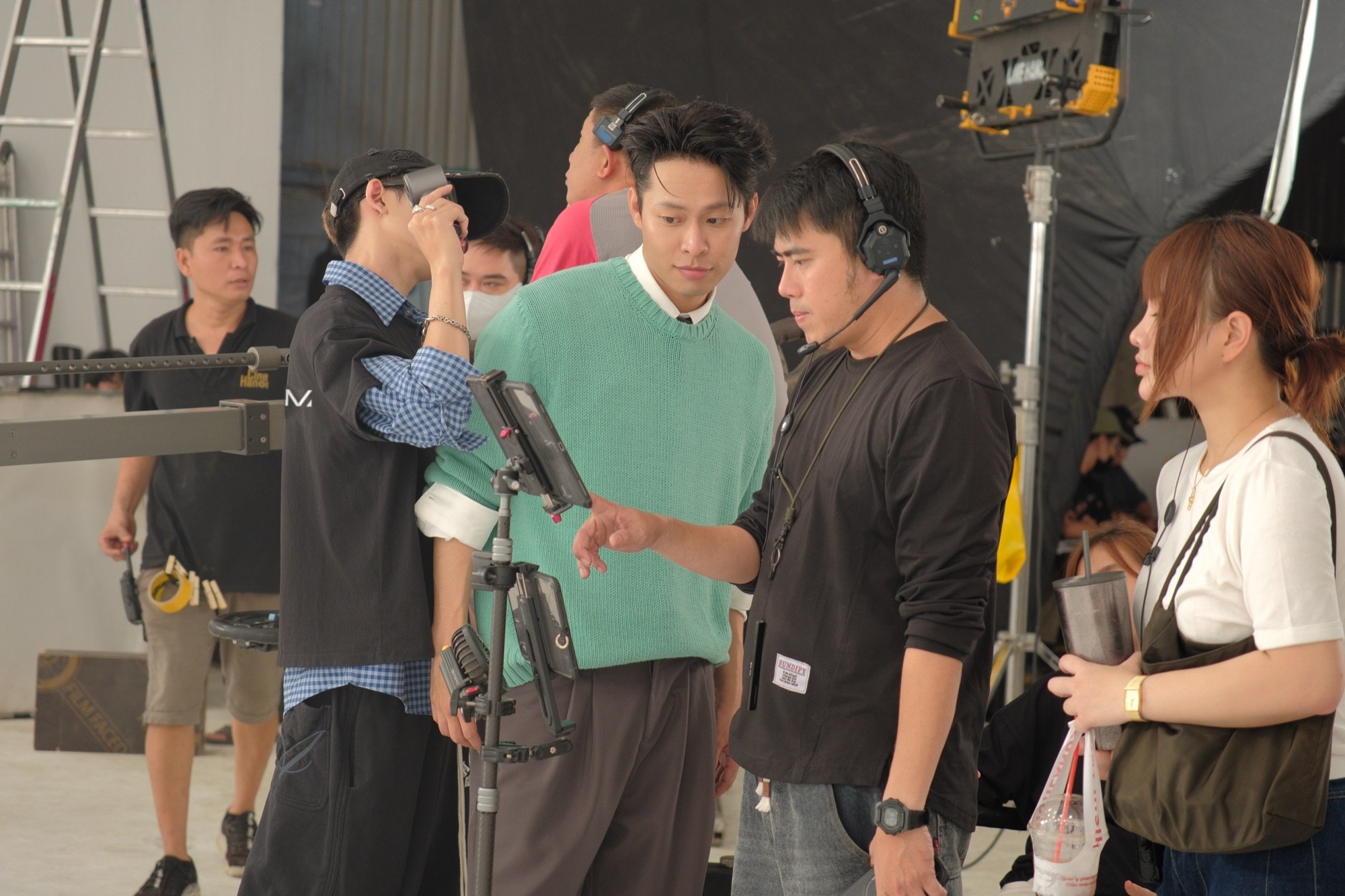 A crew member in a headset talking an actor in a green sweater through a take beside a monitor on a CeraVe studio shoot