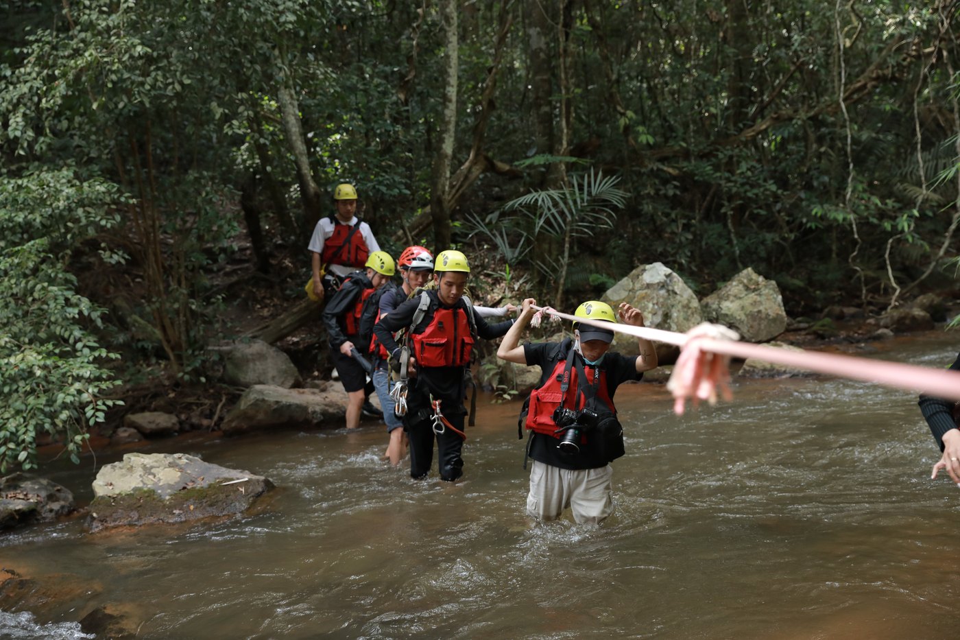 Crew and talent crossing a mountain stream on ropes during a location shoot in Da Lat