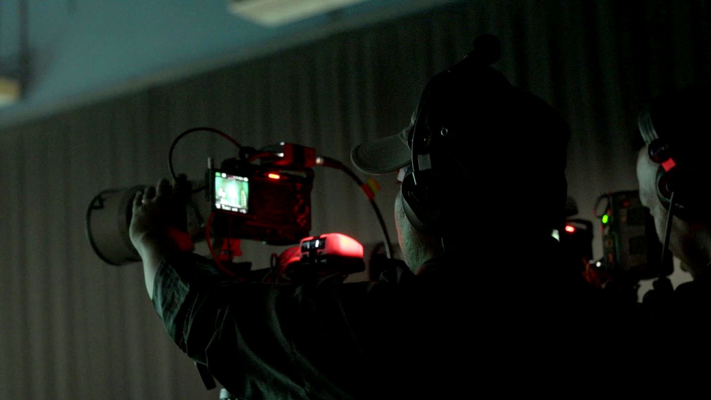 Camera operator behind a cinema camera in the dark during a live brand event