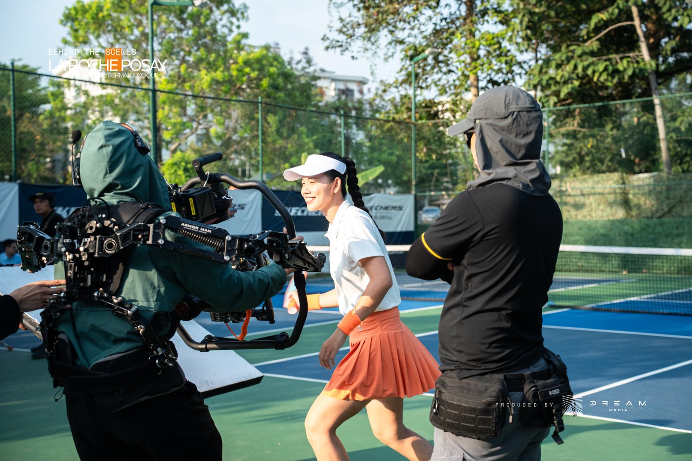 Camera operator in a stabiliser rig running alongside a tennis player on court during a La Roche-Posay shoot