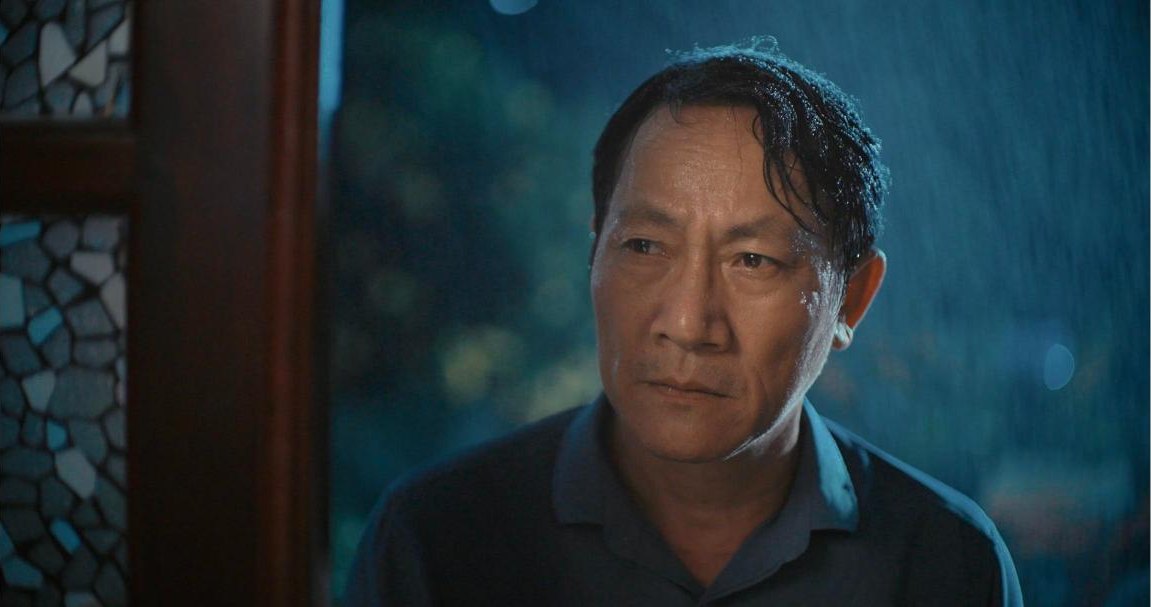 Close-up of a man with wet hair at night, with rain lit from behind falling past him, from the short film Thương Phổi