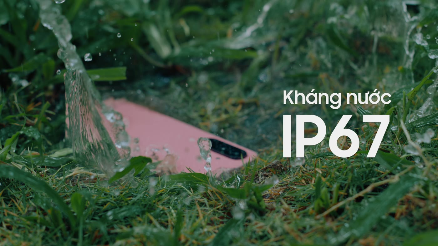 A phone lying in wet grass as water pours over it, with the words IP67 on screen, from a Samsung Galaxy A film