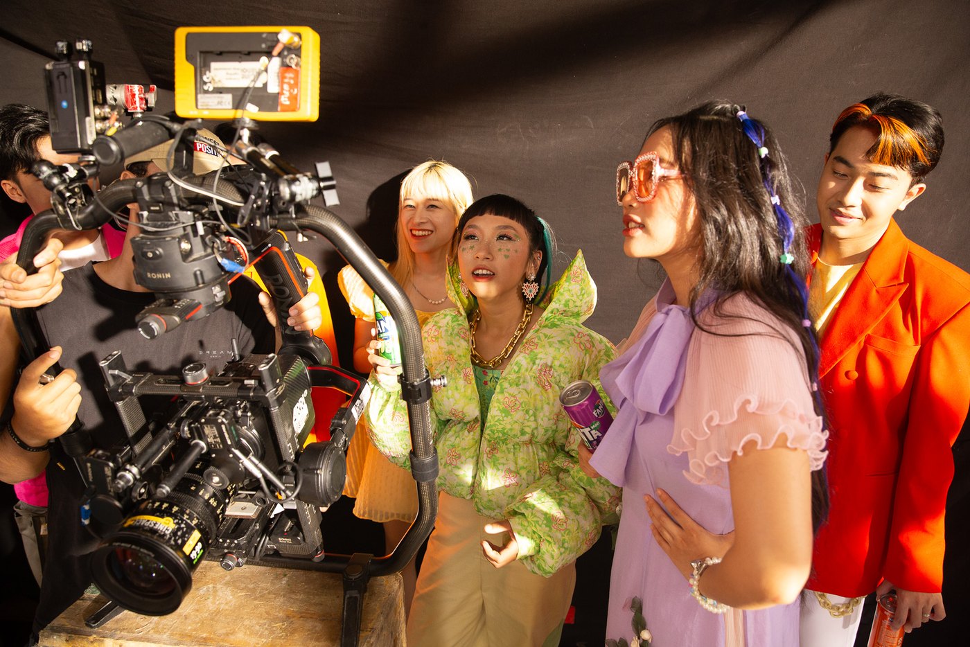 The camera on a rig close to the cast in bright costumes during a Fanta Tết shoot