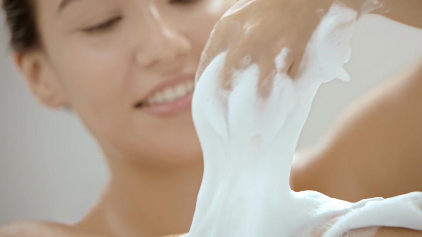Close-up of a woman applying a creamy hair treatment in a frame from a Dove film
