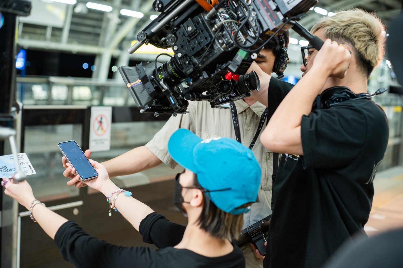 Camera operator, focus puller and crew around a cinema camera on a metro platform for a Samsung Galaxy S24 film